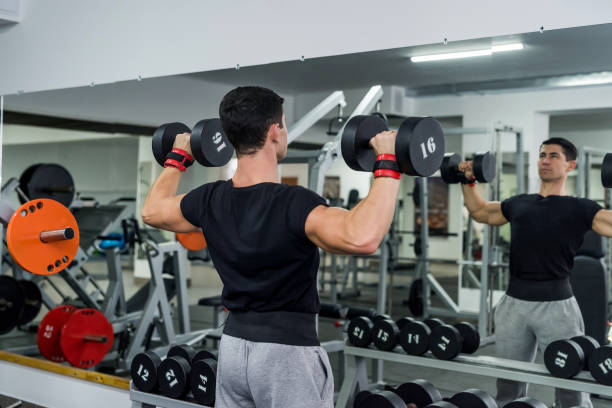 istock Athlete man lifting dumbbell in gym, back view 1166439871