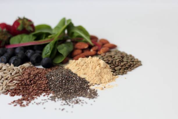PCOS diet Sample foods from low-GI PCOS (Polycystic Ovary Syndrome) diet. Lentils, almonds, chia seeds, sunflower seeds, flaxseed, maca powder, blueberries, strawberries and dark leafy greens. polycystic ovary syndrome photos stock pictures, royalty-free photos & images