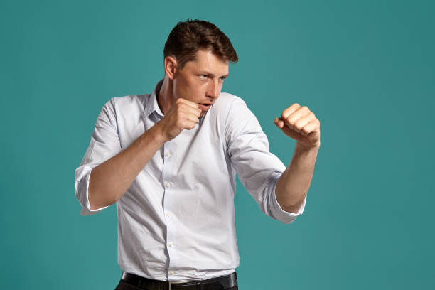 istock Young man in a classic white shirt is posing over a blue background 1166441551