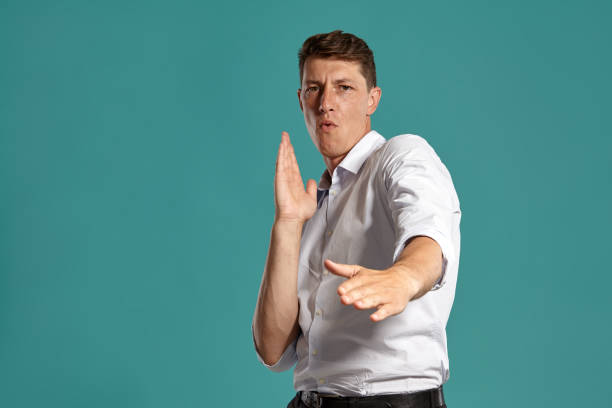 istock Young man in a classic white shirt is posing over a blue background 1166442694