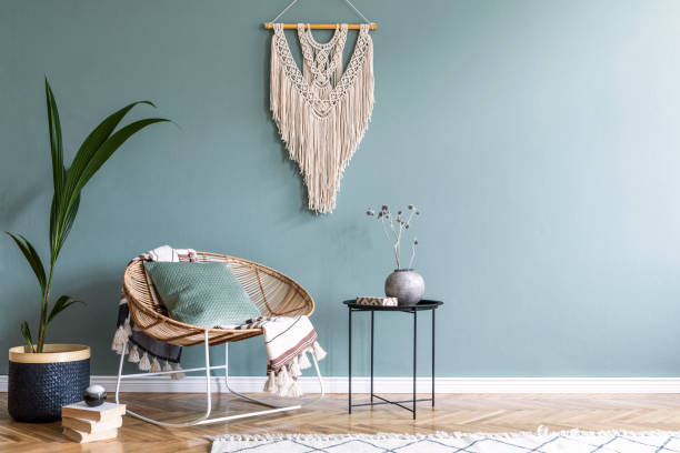 stilvolle sminimalistische inneneinrichtung des wohnzimmers mit design rattan sessel, schwarzen couchtisch, tropischen platn im korb, beige makramee an der wand und elegante accessoires. eukalyptus farbe der wand. - black coffee fotos stock-fotos und bilder