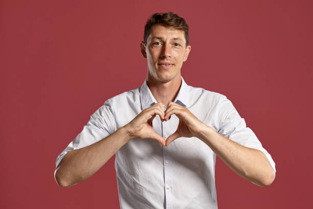 istock Young man in a classic white shirt is posing over a pink background 1166442917