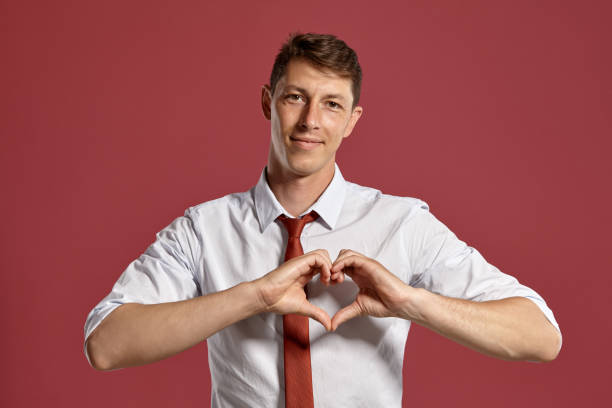 istock Young man in a classic white shirt and red tie posing over a pink background 1166443020