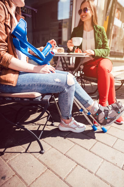 istock Two women, one with a broken leg and crutches, in a cafe 1166444365