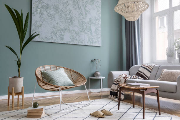 modern och bohemisk komposition av inredningsdesign med grå soffa, rotting fåtölj, retro fotstöd, pläd, kudde, tropiska växter, litet bord och eleganta accessoarer. snygg heminredning. mall. - personliga tillbehör fotografier bildbanksfoton och bilder