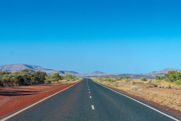 Dark tarmac road in Australian Outback around Cheela Plains Karijini National Park stock photo