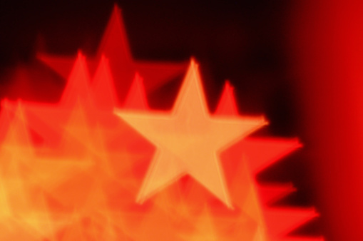 Red star shapes abstract bokeh blur. Christmas background.
