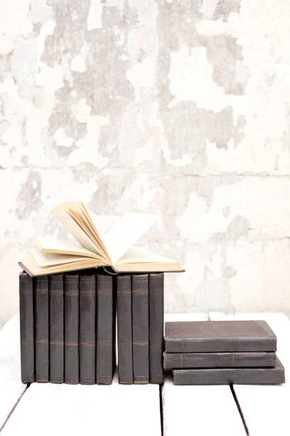 istock Stack of old ancient shabby books on a white wooden background. 1166446783