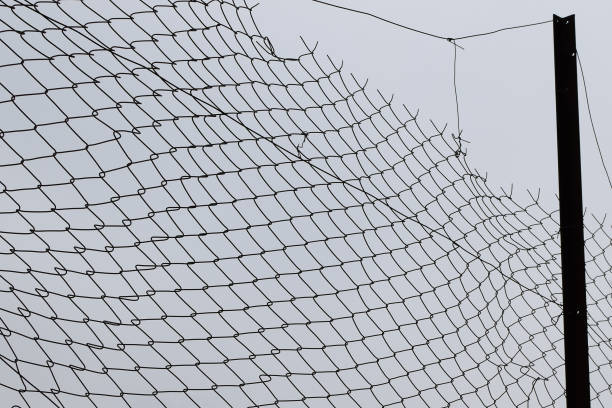 istock damaged barbed wire chain link fence background 1166452644