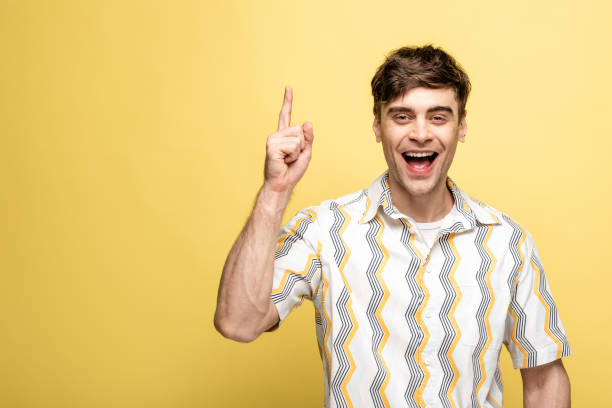 istock cheerful young man showing idea sign while smiling at camera on yellow background 1166455352