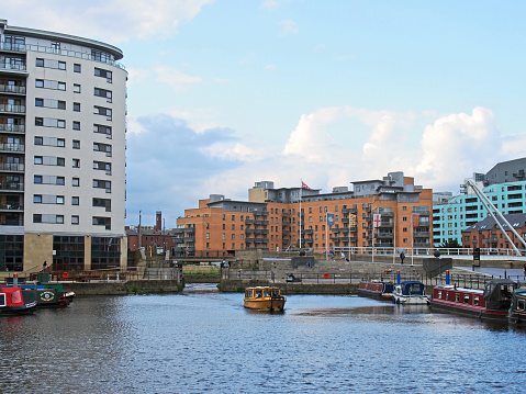 leeds, west yorkshire, united kingdom - 16 july 2019: a view of the lock gates at leeds dock with a yellow water taxi and houseboats moored along the dockside