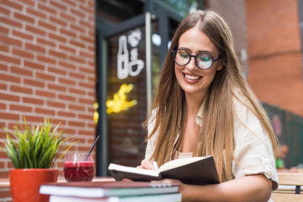 istock Beautiful young woman taking notes in her diary at cafe garden. 1166461726
