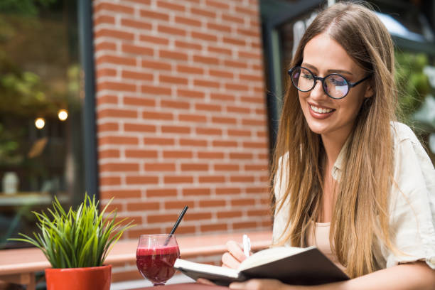 istock Beautiful young woman taking notes in her diary at cafe garden. 1166461788