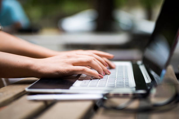 istock Unrecognizable young woman doing creative work on laptop at coffee shop garden. 1166461878
