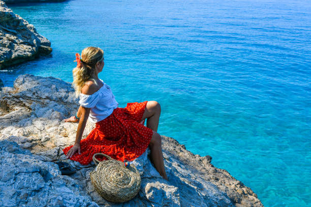 Woman sitting on rocks at the beach.