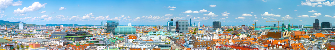 Aerial panoramic cityscape view of austrian capital city of Vienna. Summertime sunshine day, small cumulus clouds in the blue sky.