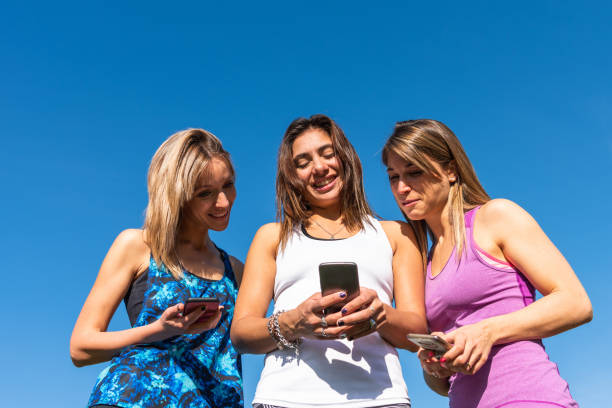 istock Three happy young women watching the smart phone with a blue sky 1166472081