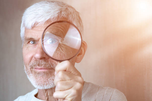 istock a gray-haired man in light clothes looking through a magnifying glass 1166473077