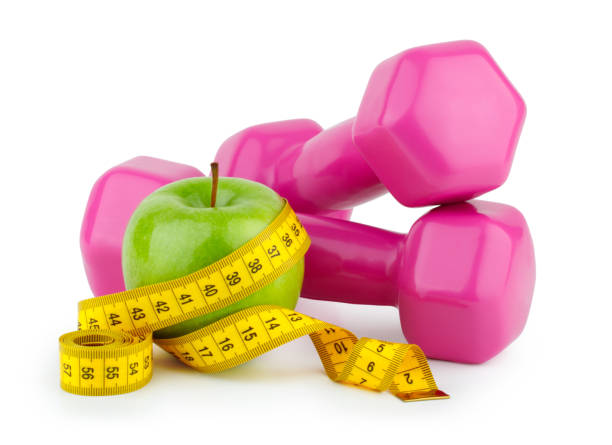 dieta, fitness e concetto sportivo. manubrio rosa, metro e mela su sfondo bianco - weights dieting apple healthy eating foto e immagini stock