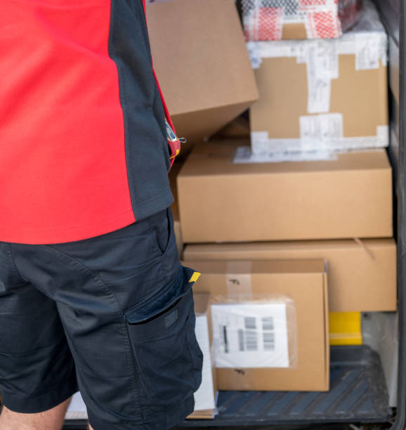 Taking cardboard box out of delivery van Rear view of unrecognizable man taking cardboard box out of delivery van, Nikon Z7 mover delivery person box hand truck stock pictures, royalty-free photos & images
