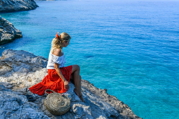 istock Woman sitting on rocks at the beach. 1166475507