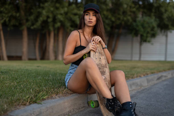 istock Young skateboarder woman sitting with her skateboard 1166475803