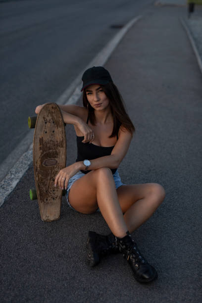istock Young skateboarder woman sitting with her skateboard 1166475808
