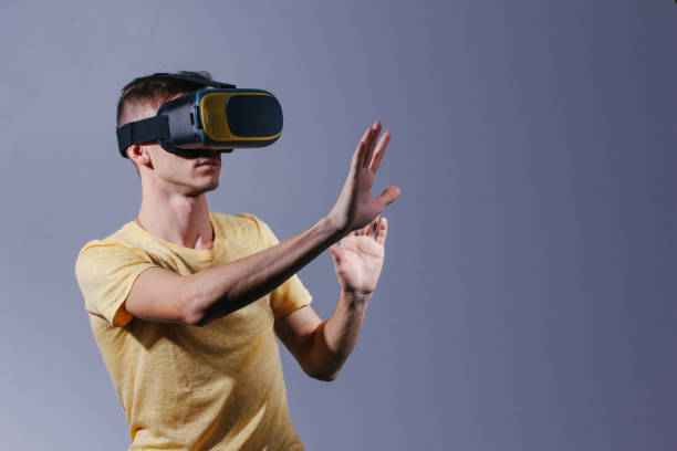 istock technology, gaming, entertainment and people concept - young man with virtual reality headset or 3d glasses. Studio shot, gray background. 1166477185