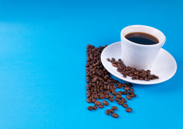 istock A cup of black coffee with grains near it on a blue background 1166477453