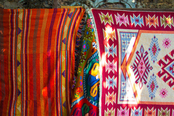 istock Carpets embroidered from threads of various bright colors. Carpets are hung on a stone wall in a Turkish market. Carpets are embroidered from threads of natural origin. 1166477482