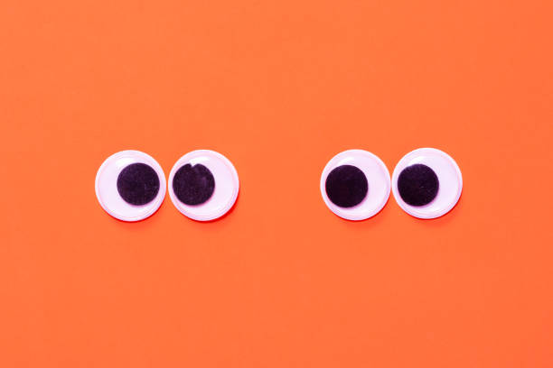 Googly eyes: One pair strabismus and squint mad googly eyes and one pair normal funny eyes next to each other on a orange background.