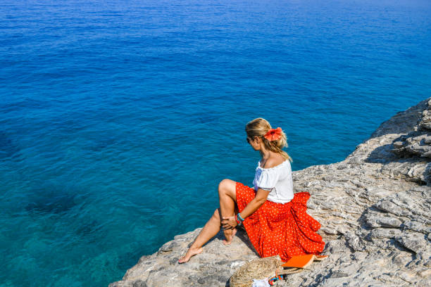 istock Woman sitting on rocks at the beach. 1166479063
