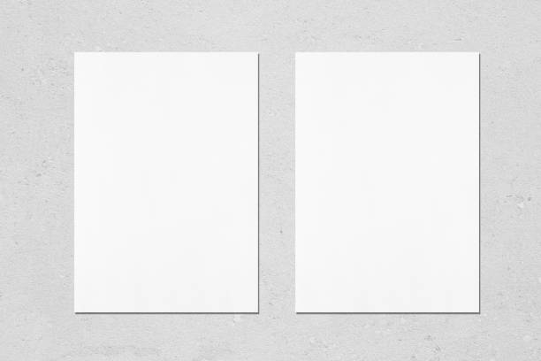Two empty white vertical rectangle poster mockups on light grey concrete background Two empty white vertical rectangle poster mockups with soft shadows on neutral light grey concrete wall background. Flat lay, top view a4 paper stock pictures, royalty-free photos & images