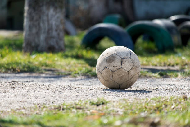 Old shabby leather soccer ball lying on the ground