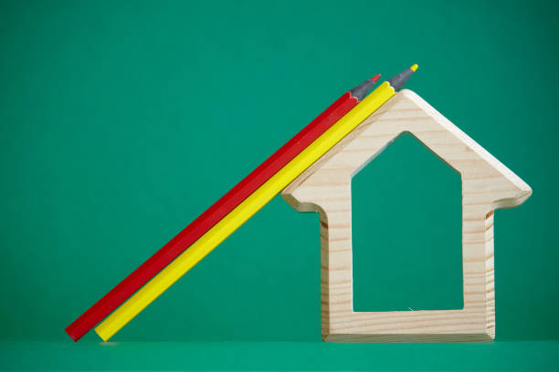 istock Wooden house figurine and several colored pencils isolate on green background, concept back to school, selective focus 1166482297