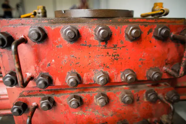 Shallow depth of field image with worn out heavy iron industrial equipment used in the oil and gas drilling industry (rusty bolts, nuts, pipes, levers)