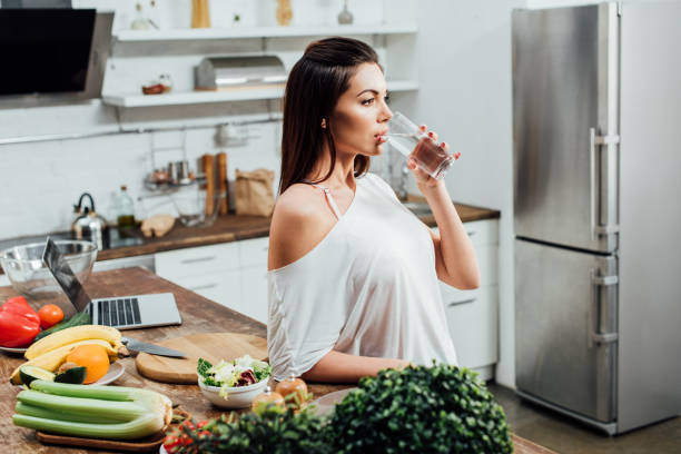istock Pensive attractive woman drinking water near table in kitchen 1166488673