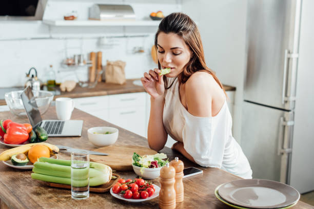istock Pensive girl sitting at table and eating salad in kitchen 1166488699