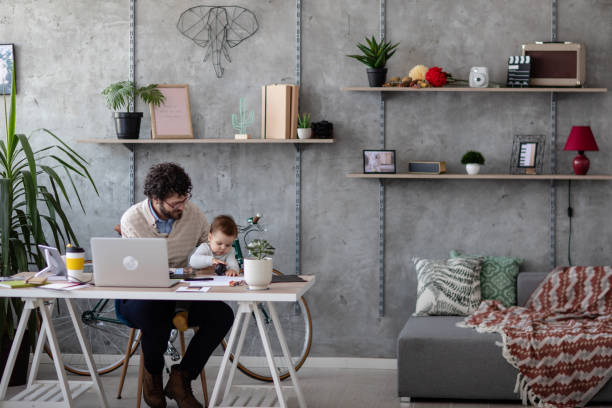istock Father holding his baby and working from hone office 1166489633