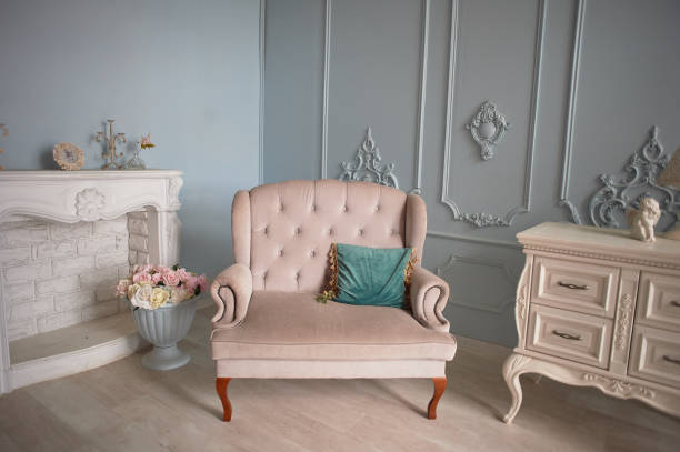 istock Sofa upholstered in fabric, light classic interior. The walls are decorated with molding.Decorative fireplace and chest of drawers 1166489713