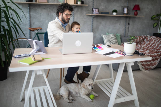 istock Father holding son and working in home office 1166491179