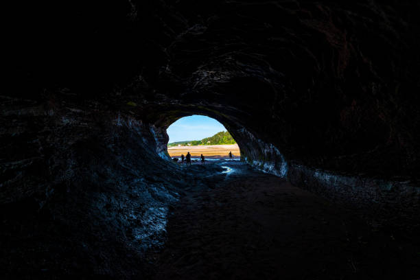Looking Out From A Sea Cave Looking out from inside a sea cave. Bright sunny day outside. The walls of the cave are wet and reflect light from the outside. Unidentifiable people in the entrance. Wide angle from the back. st. martins stock pictures, royalty-free photos & images