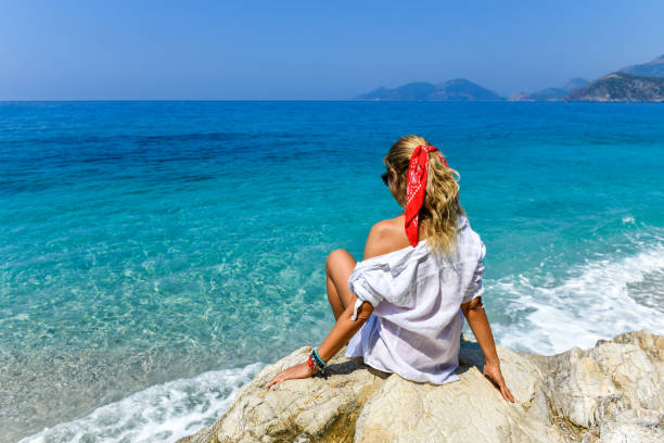 Woman sitting on rocks at the beach.