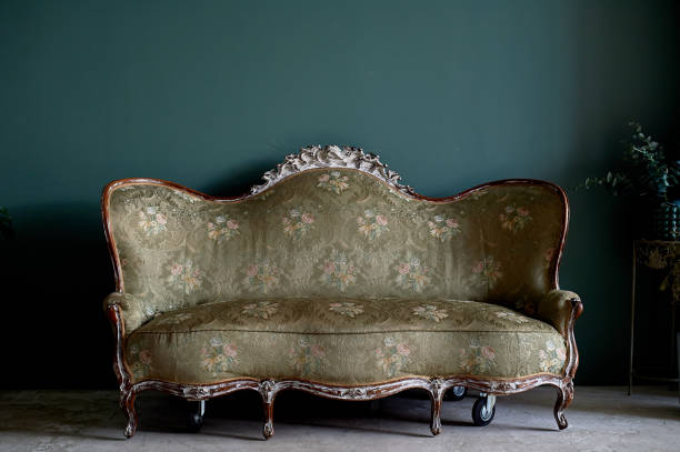 istock Old couch with a sharp wood, upholstered fabric. Against the green wall.Retro interior 1166492844
