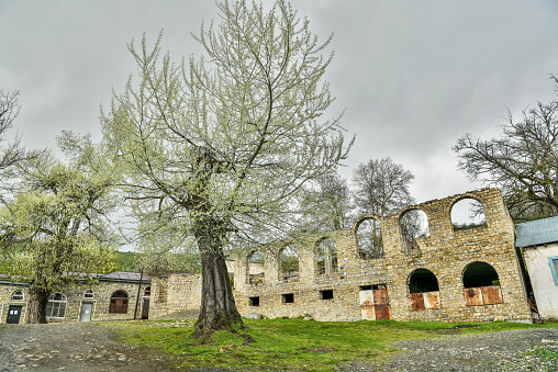 Main square of Basqal settlement of Ismailli region of Azerbaijan, with trees and ruins of a historic building.