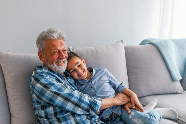 abuelo y nieto jugando y sonriendo en casa - whispering grandparent child grandfather fotografías e imágenes de stock