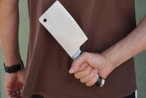 a man in brown clothes holds a large cleaver in his hand