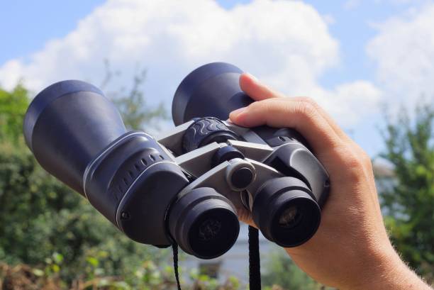 istock hand holds big black binoculars against the sky 1166496982