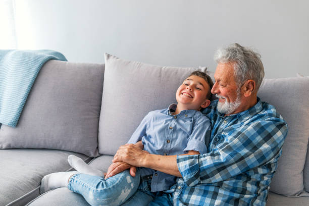 nonno che abbraccia suo nipote - whispering grandparent child grandfather foto e immagini stock