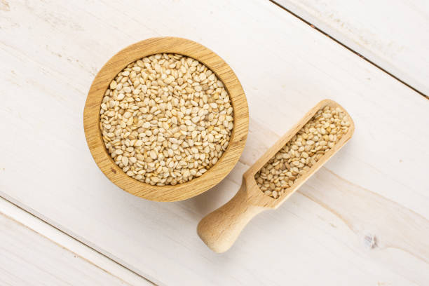Unpeeled sesame seeds on grey wood
